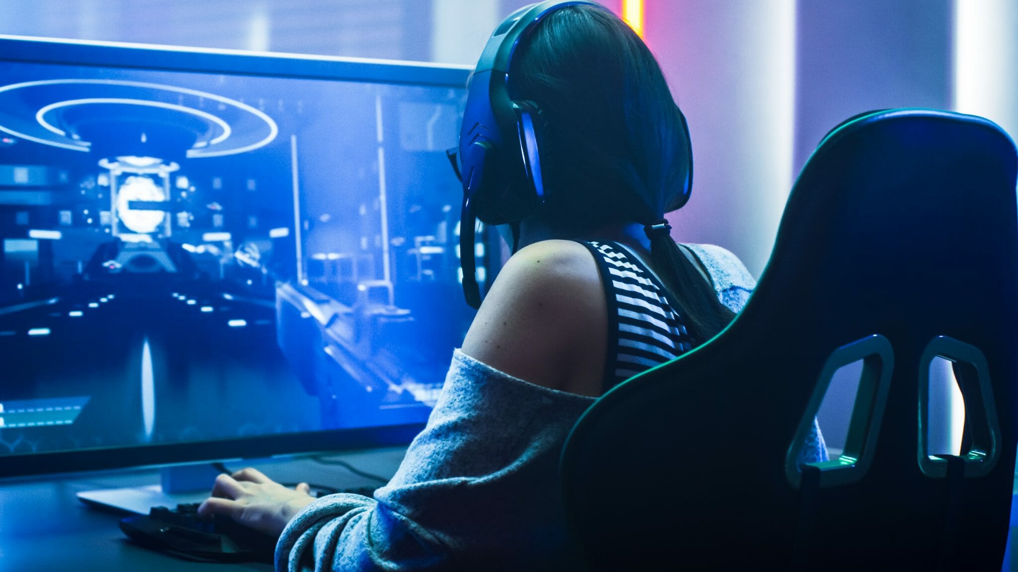 Female with back to the camera playing an FPS game on PC