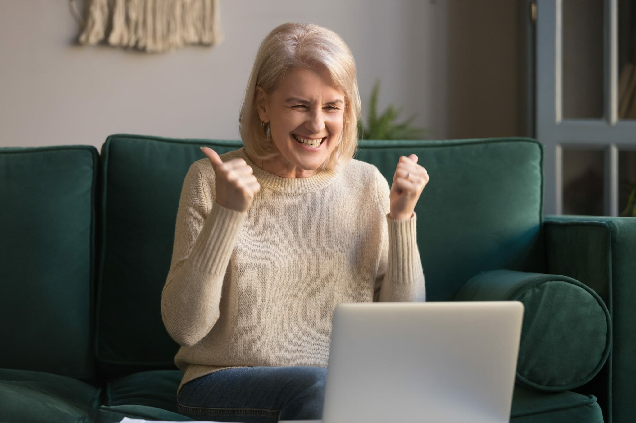 Woman giving herself a thumbs up while looking at a laptop